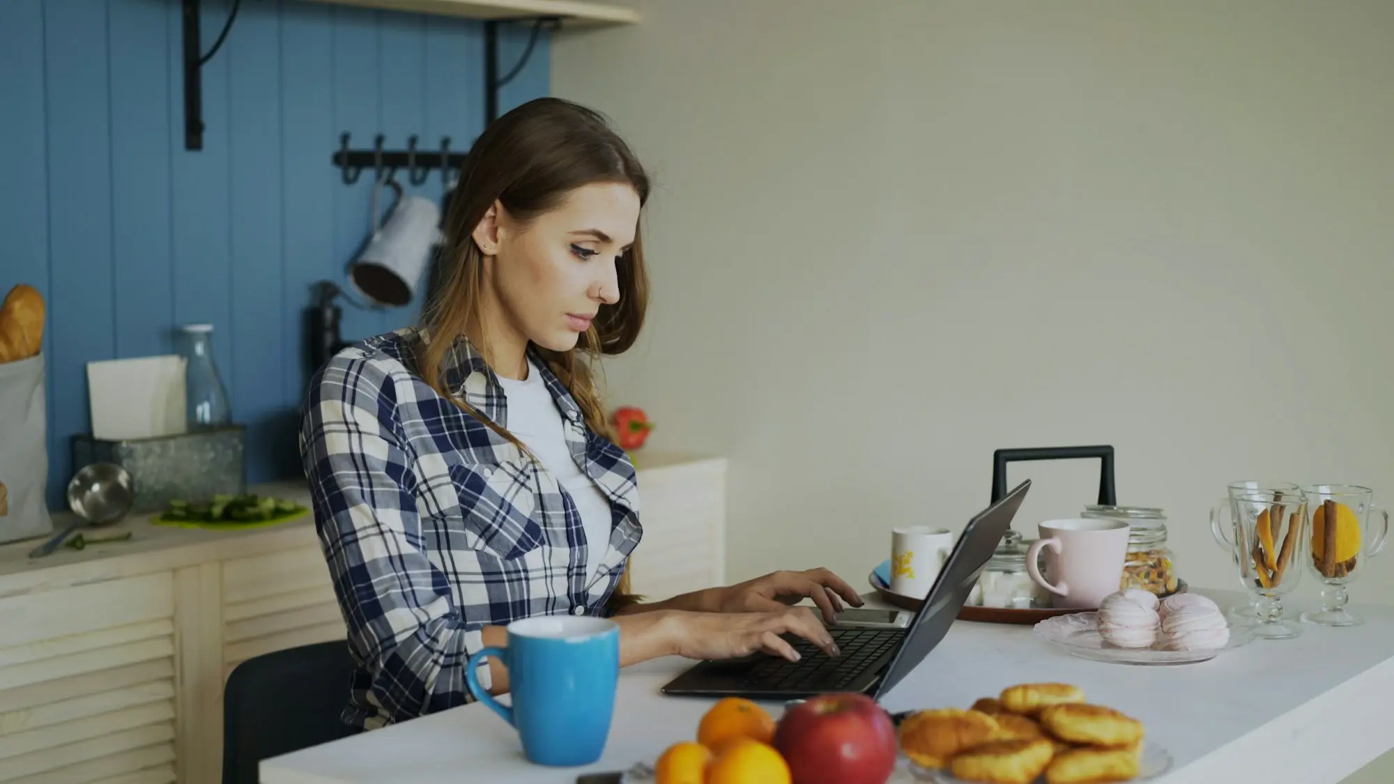 Woman working on a laptop in a bright kitchen